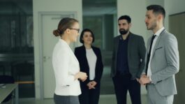 Group of professionals in formal attire having a discussion in a modern office setting.