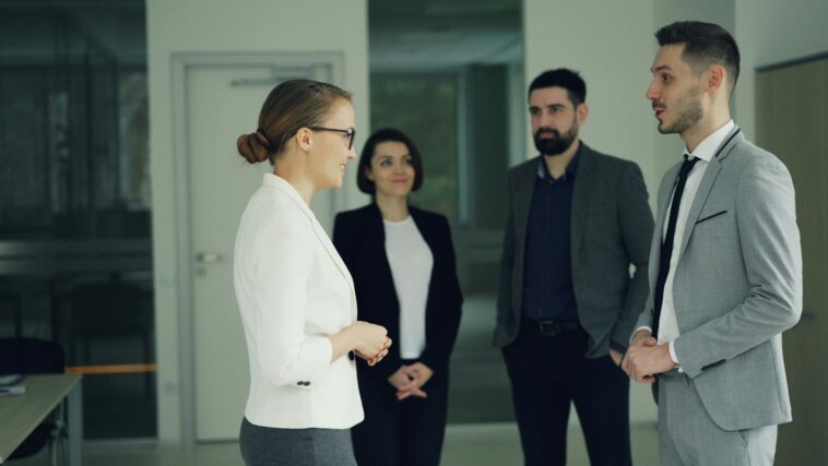 Group of professionals in formal attire having a discussion in a modern office setting.