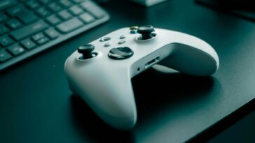 Close-up of a white game controller on a sleek desk, highlighting technology and gaming.