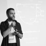 Man speaking into a microphone during a business seminar presentation.