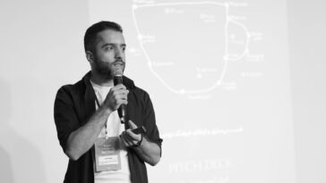 Man speaking into a microphone during a business seminar presentation.