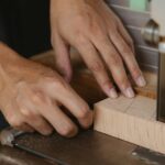 Close-up of hands using a bandsaw on wood in a workshop. Ideal for woodworking themes.