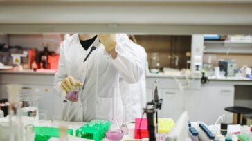 Scientist in a lab coat handling samples for scientific research in a modern laboratory setting.