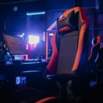 Modern gaming setup featuring a sleek chair and powerful PCs under neon lights.