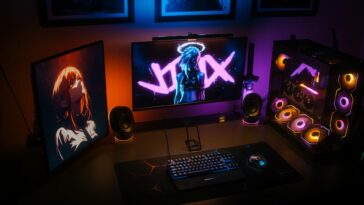 A modern gaming setup featuring RGB lighting, dual monitors, and a custom PC with colorful components.