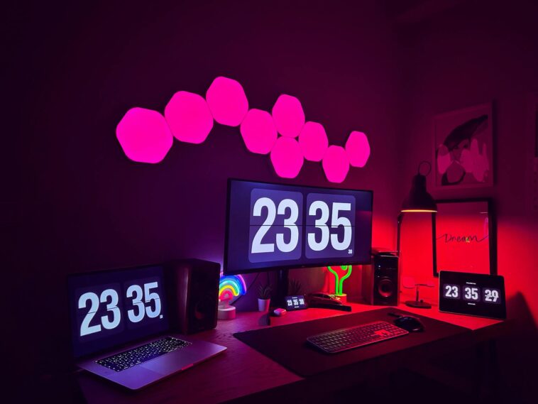A stylish modern workspace featuring multiple screens, neon lights, and digital clocks.