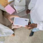 Adults exchanging a smartphone gift indoors, highlighting modern technology and joyful sharing.