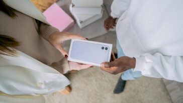 Adults exchanging a smartphone gift indoors, highlighting modern technology and joyful sharing.