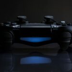 Close-up of a gaming controller with a soft blue light in a dark setting.