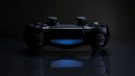 Close-up of a gaming controller with a soft blue light in a dark setting.