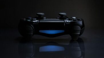 Close-up of a gaming controller with a soft blue light in a dark setting.