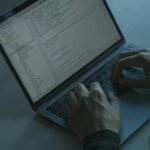 A person typing code on a laptop with a focus on cybersecurity and software development.