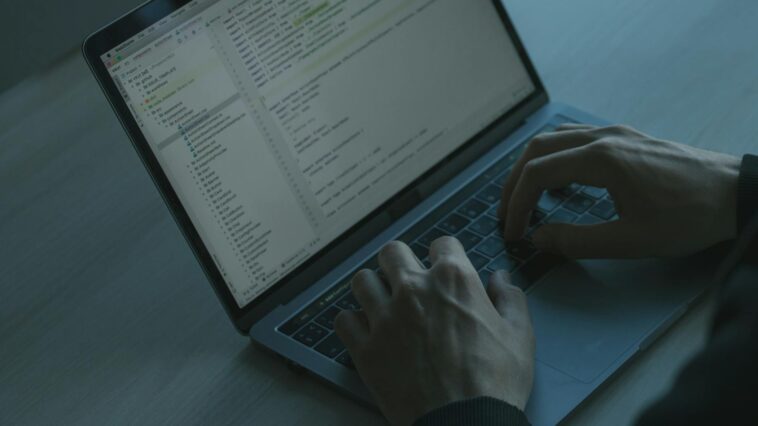 A person typing code on a laptop with a focus on cybersecurity and software development.