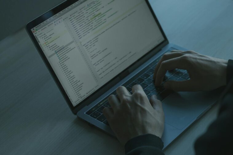 A person typing code on a laptop with a focus on cybersecurity and software development.