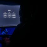 Silhouette of a person using ChatGPT on a computer screen in a dark room, highlighting digital interaction.