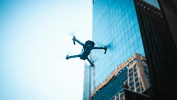 High-tech drone operating near a modern skyscraper captures urban technology in action.
