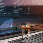 Laptop screen displaying code and performance graphs with eyeglasses resting on the keyboard.