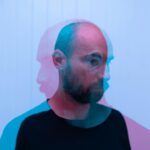 Through glass double exposure view of dreamy middle aged bearded male looking away on white background