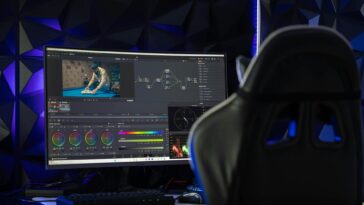 Curved monitor displaying video editing software in a tech-savvy workspace with mood lighting.