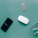 Flat lay of smartphone, cards, and shopping cart on green. Perfect for e-commerce and online shopping themes.