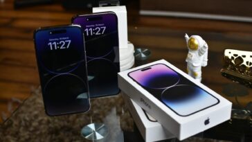 Close-up of Apple iPhone 14 Pro Max with astronaut figurine on a reflective surface.