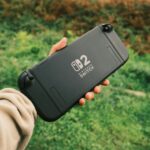 Person holding a Nintendo Switch in a natural outdoor setting, perfect for on-the-go gaming.