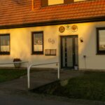 A well-lit, picturesque entrance of a modern home in Achim, Germany during sunset.