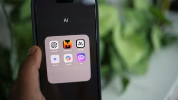 Close-up of a hand holding a smartphone with AI applications on screen.