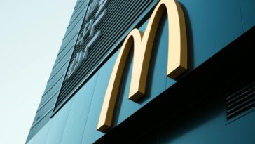 Large fast food restaurant golden arch sign on a modern building facade.