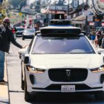 A self-driving car navigates through a bustling city street in San Francisco, capturing urban mobility in action.