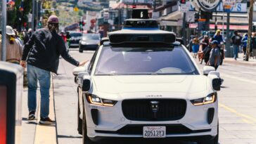 A self-driving car navigates through a bustling city street in San Francisco, capturing urban mobility in action.