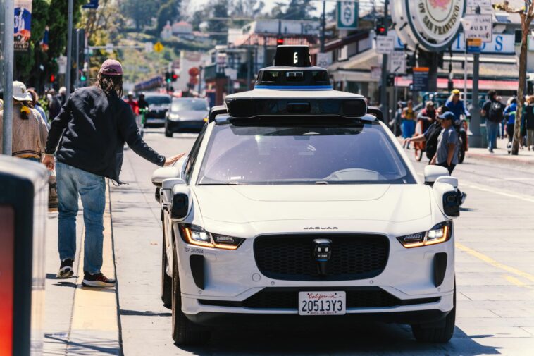A self-driving car navigates through a bustling city street in San Francisco, capturing urban mobility in action.
