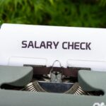 Close-up of a vintage typewriter typing 'Salary Check' on paper, symbolizing payroll and finance.