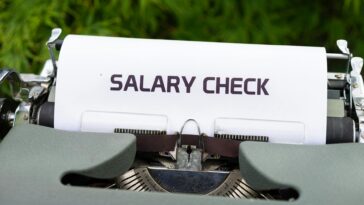 Close-up of a vintage typewriter typing 'Salary Check' on paper, symbolizing payroll and finance.