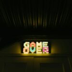 Glowing neon sign with pixelated Game Over text in a dark arcade setting.