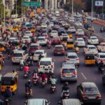 A crowded city street filled with cars, motorcycles, and buses during daytime rush hour.