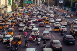 A crowded city street filled with cars, motorcycles, and buses during daytime rush hour.