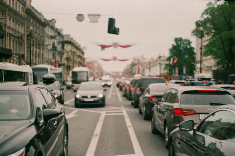 Long line of cars forming a heavy traffic jam in a bustling city center, showcasing urban congestion.