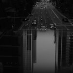 A striking black and white image of a busy urban street with modern skyscrapers and vehicles in motion.