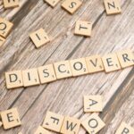Wooden tiles spelling 'DISCOVER' arranged neatly on a rustic surface.