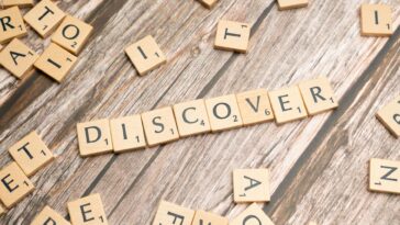 Wooden tiles spelling 'DISCOVER' arranged neatly on a rustic surface.