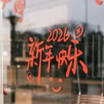 Red Chinese characters with 2026 on a glass door, symbolizing New Year celebrations.