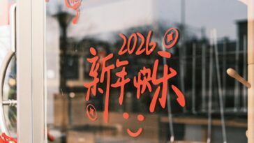 Red Chinese characters with 2026 on a glass door, symbolizing New Year celebrations.