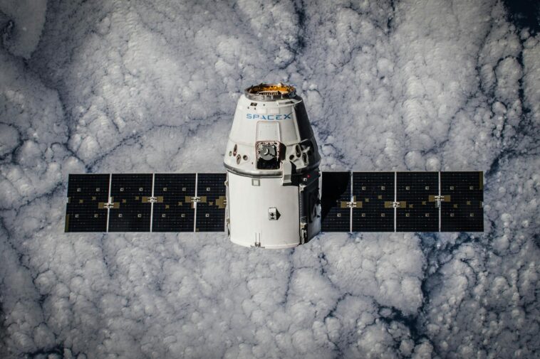 SpaceX Dragon spacecraft in orbit, highlighting advanced space technology with cloud backdrop.