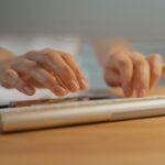 Close-up of hands typing on a white keyboard, showcasing modern technology and productivity.