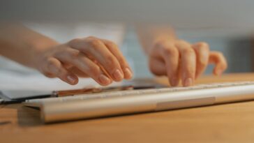 Close-up of hands typing on a white keyboard, showcasing modern technology and productivity.