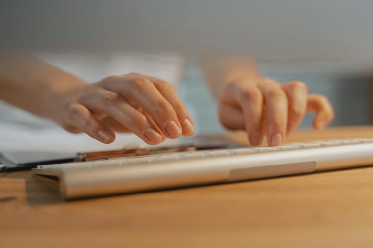 Close-up of hands typing on a white keyboard, showcasing modern technology and productivity.