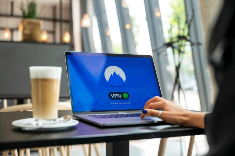 A person using a laptop with a VPN connection in a modern cafe setting, showcasing remote work and internet security.